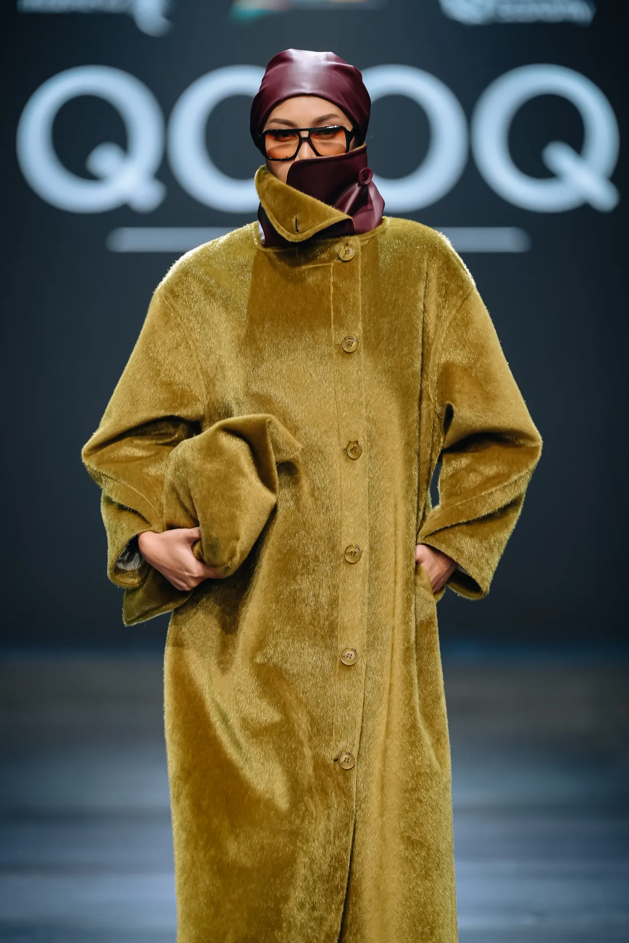 Gina on the runway in a mustard velvet coat with a matching clutch