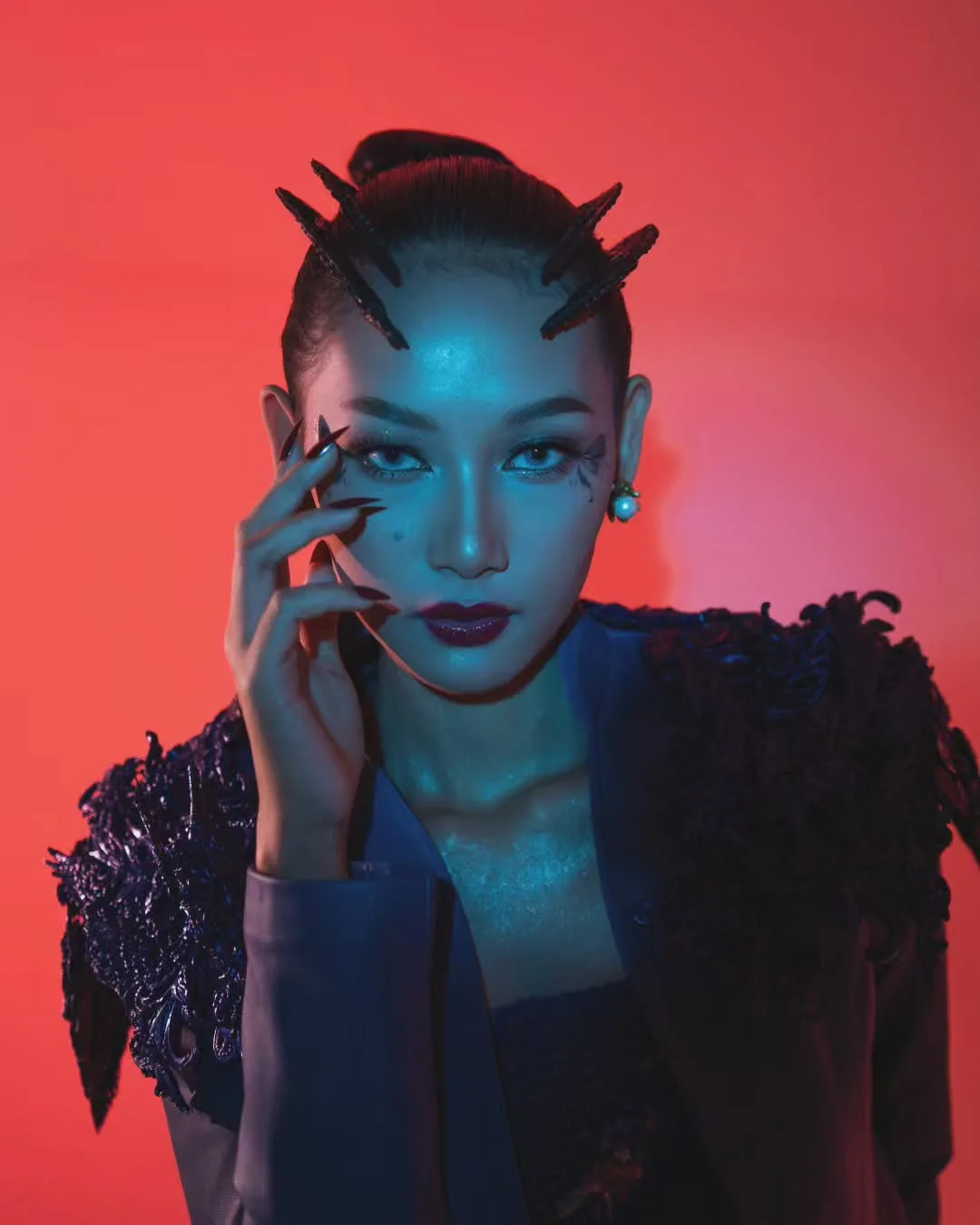 Cyberpunk inspired beauty shot of model with horn hair buns under dramatic red and cyan neon lighting